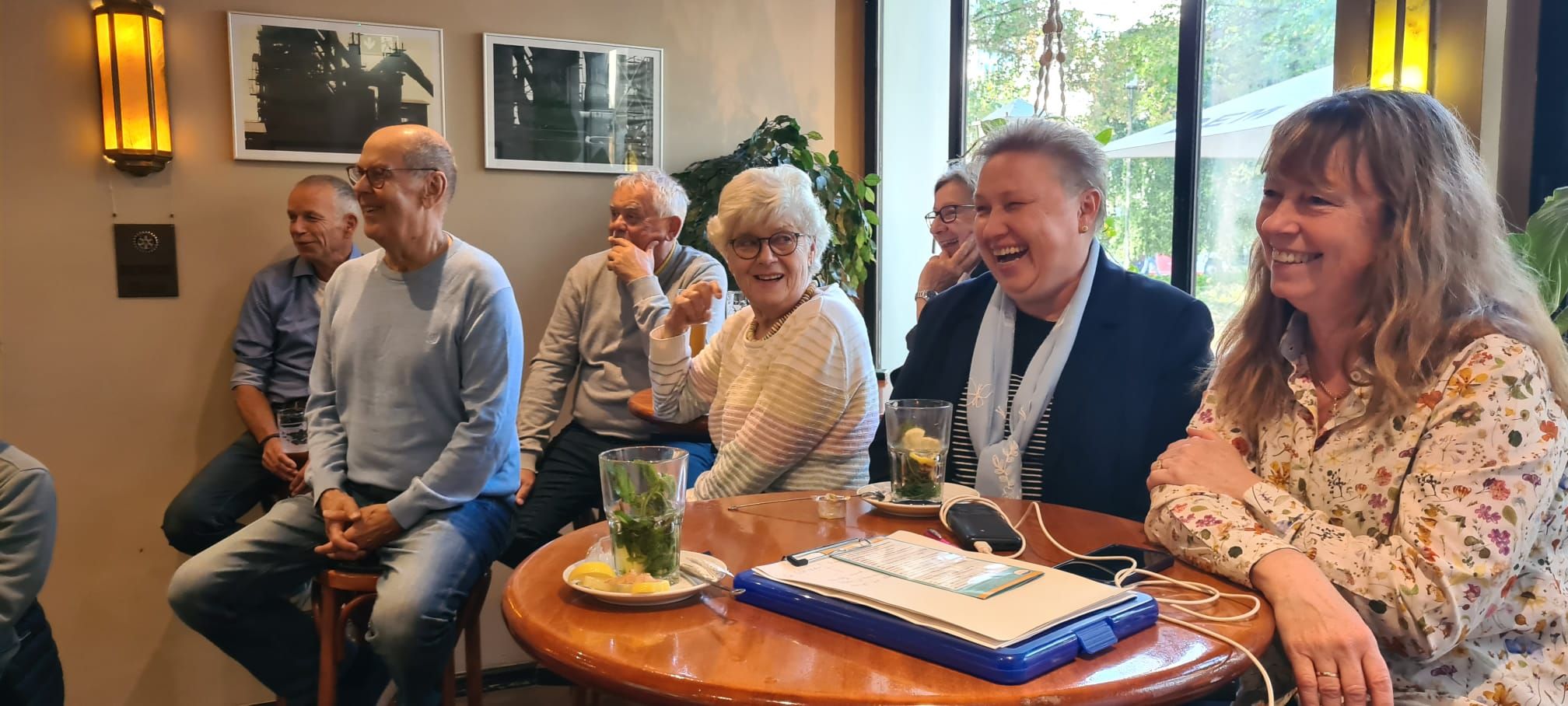 Fröhliche Gruppe lacht und genießt gemeinsamen Moment in gemütlichem Café.